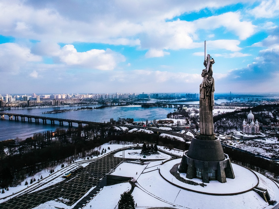 A statue of a woman overlooking a river in Ukraine