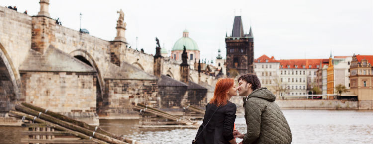 Couple kissing beside the Charles Bridge in Prague