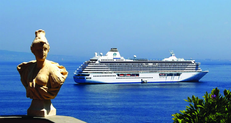 The Crystal Serenity behind see off in the distance with a statue seen in the foreground.