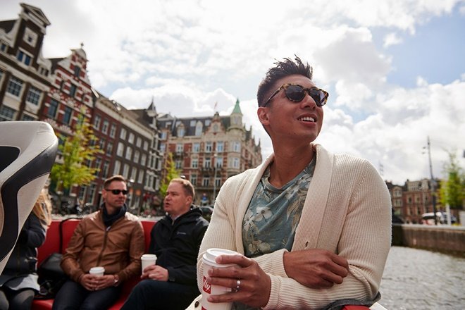 A man on the top deck of a river cruise in Amsterdam. 