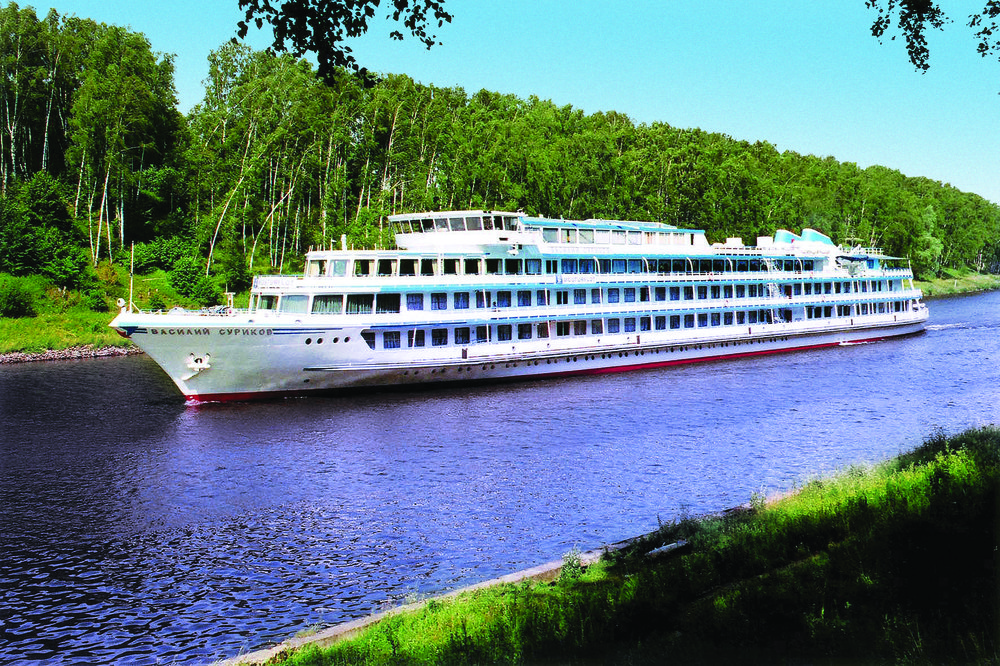 Saga cruise line ship sailing along a river lined with leafy trees