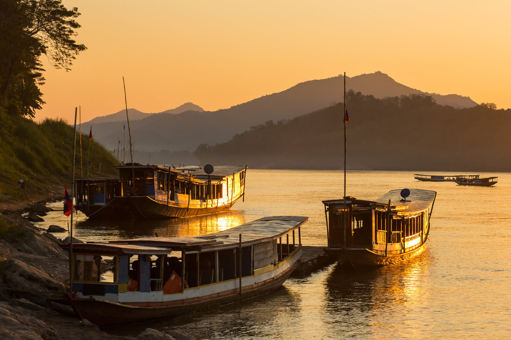 Mekong river, Luang Prabang, Laos at sunset with three boats in the harbour. 