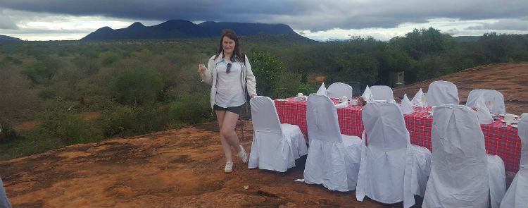 A girl on a hill in Africa wearing a shirt shirt and khaki shorts