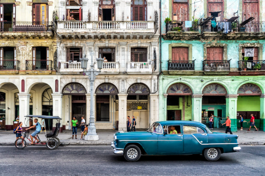 Buildings in Havana Cuba with a blue car outside them. 