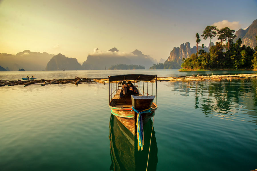A traditional boat in a secluded part of Thailand while the sun sets. 