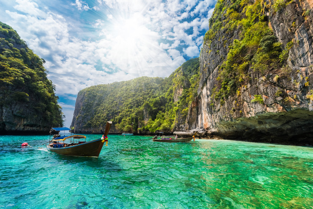 A rocky cove in Thailand with traditional boats in the water
