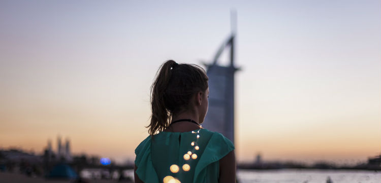 A girl with her back to the camera at sunset with the Burj Khalifa seen in the background.