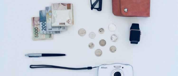 Money, a pen, coins, and a purse laid out on a white background.