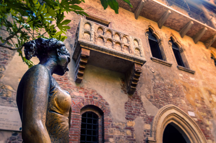 A statue of Juliet taken from a low angle with her balcony being seen up above. 