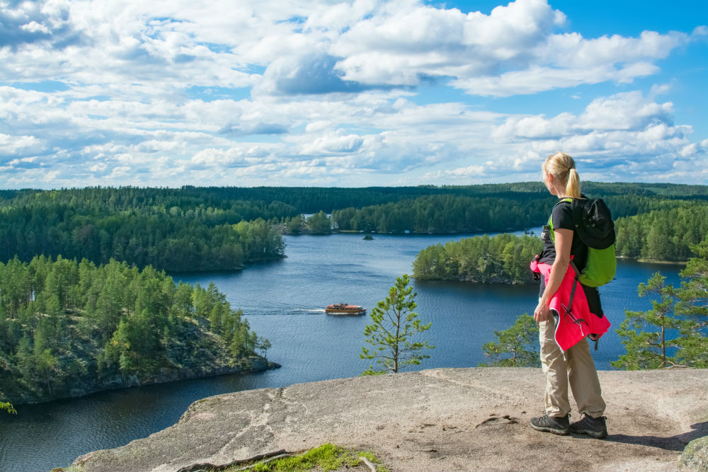 A woman standing on a rock overlooking a lake in Finland