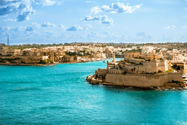 The old harbour in Malta surrounded by blue waters and old buildings. 