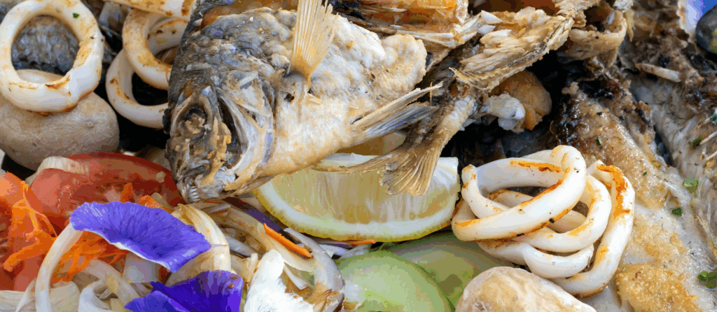 A grilled fish mix plate with various types of fish, seafood, scallops and squid rings.